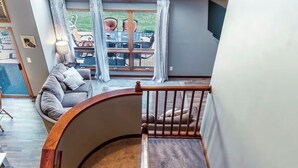 A staircase with a wooden handrail leading to a living area with a sofa and a dining table. - Galena Getaway (Galena)