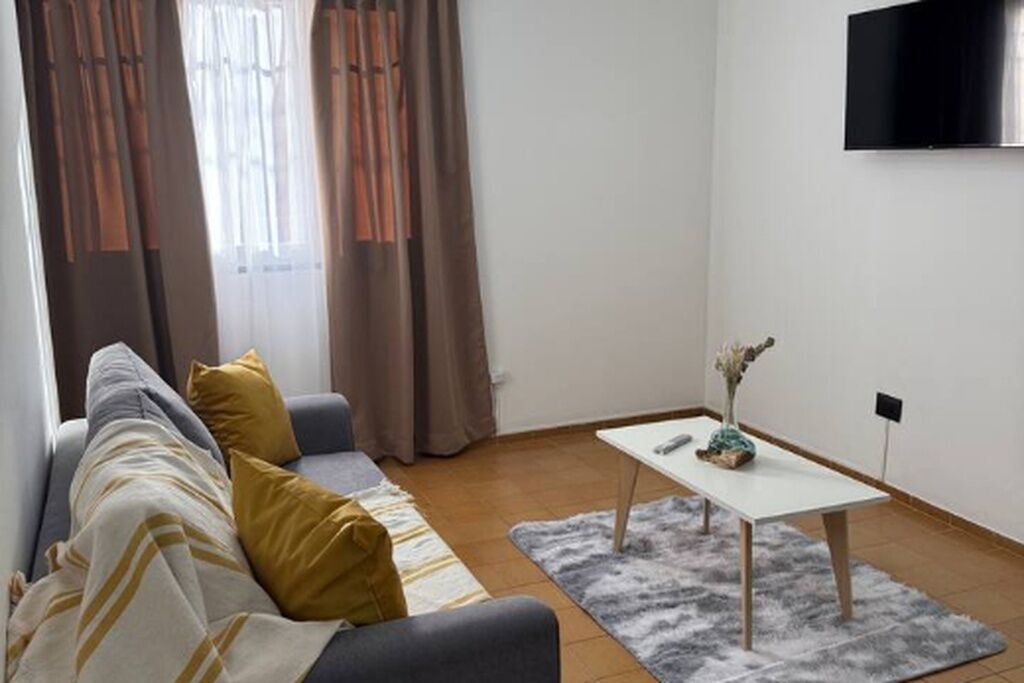 Ein modernes Wohnzimmer mit einer Couch, einem Couchtisch und einem flachbildfernseher an der Wand.