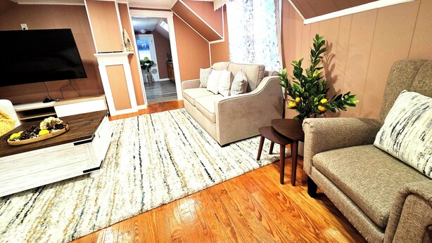A living room with a sofa, a coffee table, a TV, and a plant.