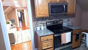 A kitchen with wooden cabinets, a stainless steel microwave, a black stove, and a granite countertop.