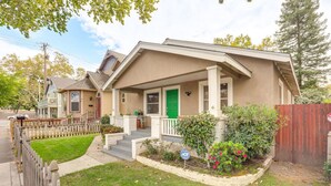 A single-story house with a front porch, a green door, and a small garden with flowers. - Midtown Oasis | BBQ, Deck, Games & Artistic Vibes (Sacramento)