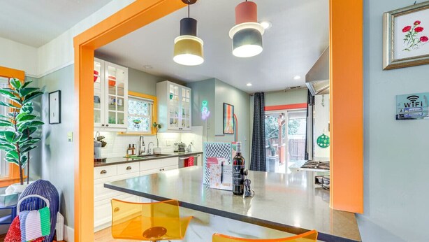 A modern kitchen with a central island, white cabinetry, and pendant lighting. - Midtown Oasis | BBQ, Deck, Games & Artistic Vibes (Sacramento)
