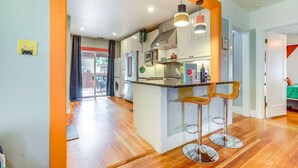 A modern kitchen with a central island, stainless steel appliances, and a bar area with stools. - Midtown Oasis | BBQ, Deck, Games & Artistic Vibes (Sacramento)