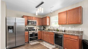 A modern kitchen with stainless steel appliances, wooden cabinets, granite countertops, and a built-in oven. - 327 Beautiful Residence in Mebane NC. (Mebane)