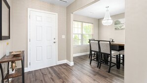 A room with a white door, a dining table with chairs, and a chandelier. - 327 Beautiful Residence in Mebane NC. (Mebane)