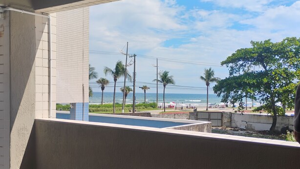 Un balcon avec vue sur la plage, les palmiers et un ciel dégagé.