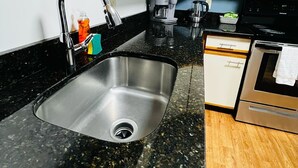 A kitchen with a stainless steel sink, a coffee maker, a microwave, and wooden cabinets. - Extended Stay- Full Kitchen 1BR apartment in Downtown Pittsfield (Pittsfield)