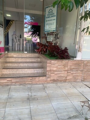 A hotel entrance with a glass door, a staircase leading up, and a signboard advertising the hotel. - Pousada Romelandia (Romelândia)