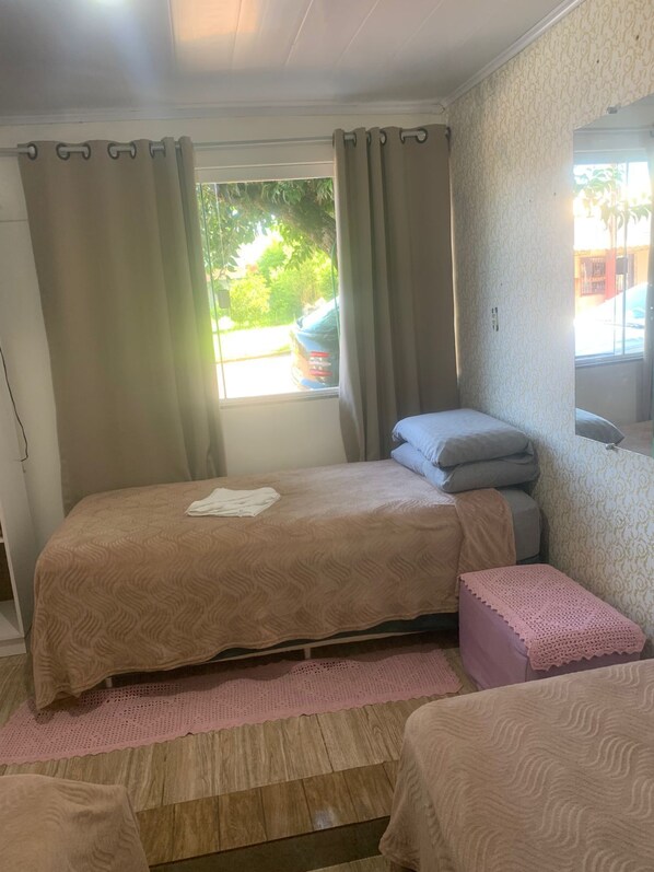 Un dormitorio con cama, un banco, una ventana con cortinas y vistas al exterior.