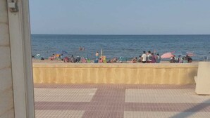A tiled floor with a view of the sea and beach umbrellas.