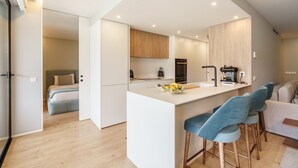 Una cocina moderna con una isla central, taburetes de bar y un área de comedor con sofá.