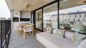 Un espacio moderno con zona de estar, sofá, mesa de comedor, sillas, un ventanal y vistas a edificios.