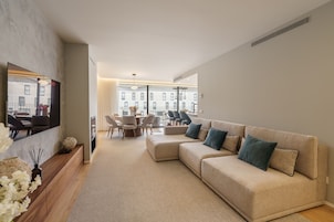 A modern living room with a beige sofa, a dining table, and chairs.