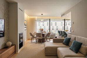 A modern living room with a sofa, dining table, chairs, and a TV.
