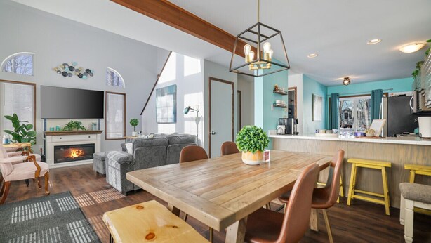 Een gezellige woonkamer met een open haard, een eetgedeelte met een houten tafel, en een keuken met een bar.