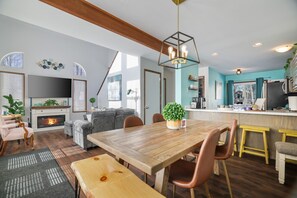 A cozy living room with a fireplace, a dining area with a wooden table, and a kitchen with a bar. - Family Fun - Pocono Getaway - Arcade - Game Room - Fire Pit (Tobyhanna)