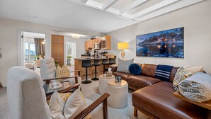 Ein modernes Wohnzimmer mit einem braunen Ledersofa, einem Glastisch und einem Essbereich mit Holzschränken und einer Kücheninsel.