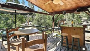 A wooden deck with a bar area, outdoor seating, and a ceiling fan. - Cozy cabin right at Lewis Creek Trail, near  Yosemite, Bass lake (Oakhurst)