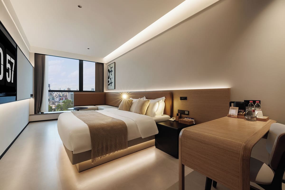 Une chambre d’hôtel moderne avec un grand lit, un bureau et une vue sur la ville.