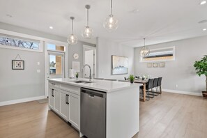 Una cucina moderna con isola centrale, mobili bianchi e illuminazione a sospensione.