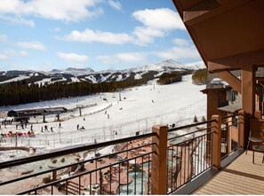 A ski resort with a snow-covered slope, a gondola lift, and a wooden deck with a railing. - Three Bedroom Ski In/Ski Out Condo at Grand Lodge on Peak 7 (Breckenridge)