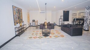 A modern living room with a marble floor, a central coffee table, a sofa, and a decorative rug. - Noble Nook Boutique Hotel (Abuja)