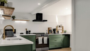 A modern kitchen with green cabinets, a stainless steel sink, and a black stove. - Secluded White Mtns Retreat • Hot Tub • Sleeps 10 • Pet Friendly (Albany)