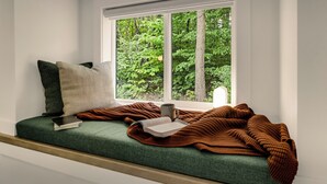 A window seat with a book, a mug, and a blanket. - Secluded White Mtns Retreat • Hot Tub • Sleeps 10 • Pet Friendly (Albany)