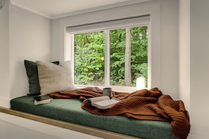 Un coin confortable près d’une fenêtre, avec un livre, une tasse et une couverture.