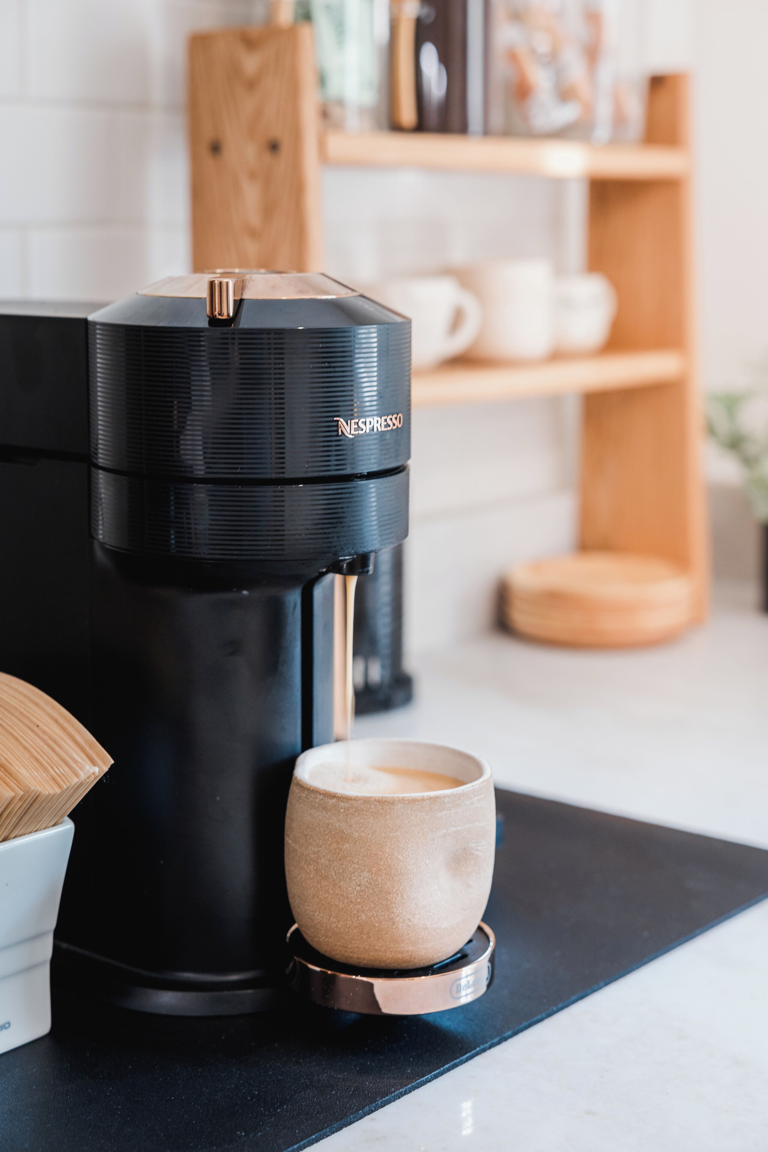 A Nespresso coffee machine with a cup on a coaster.