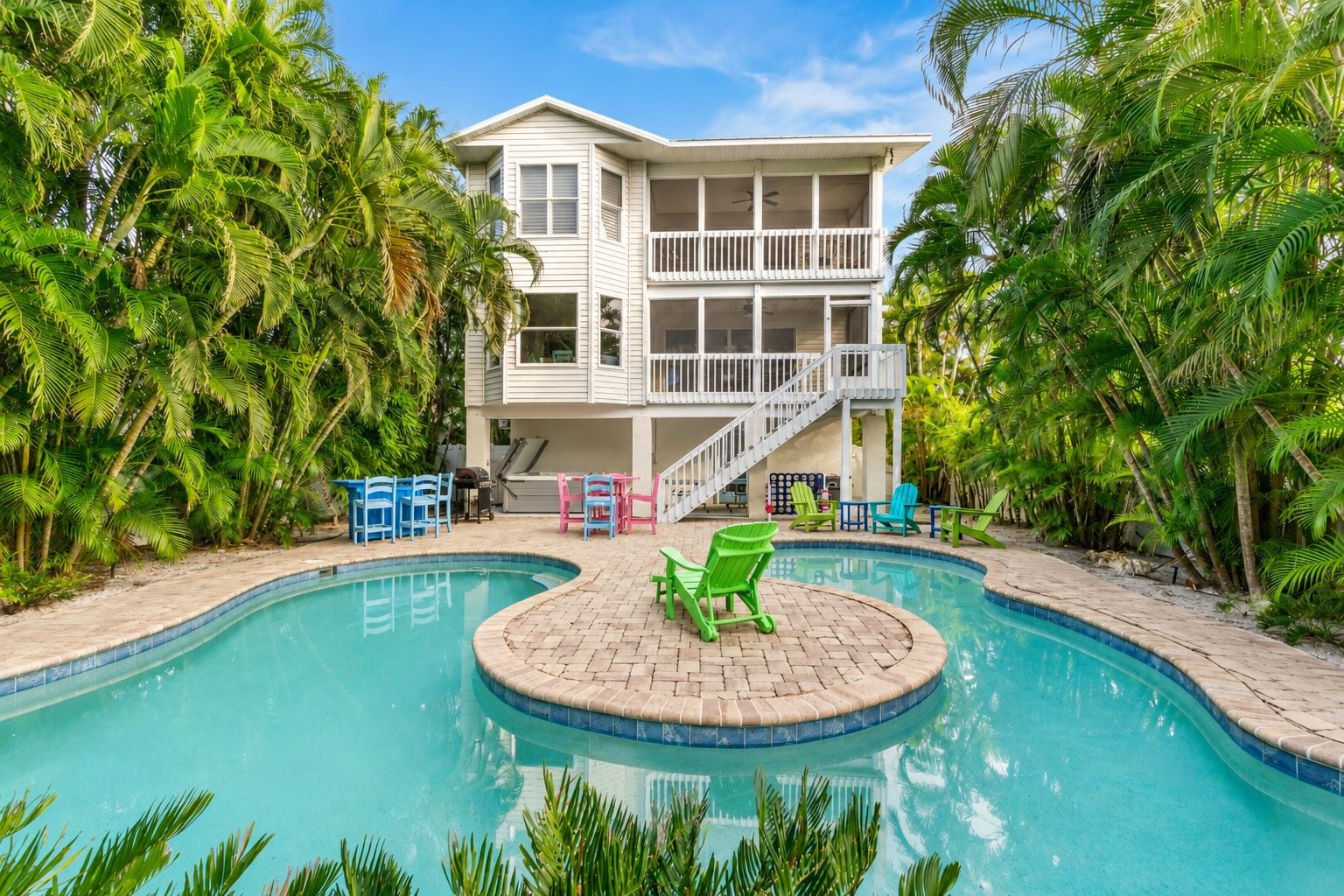 A two-story house with a pool, surrounded by palm trees.