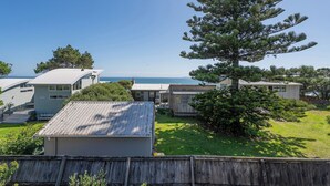 Un quartier résidentiel situé sur la côte, avec plusieurs maisons, un grand pin et une vue dégagée sur la mer.