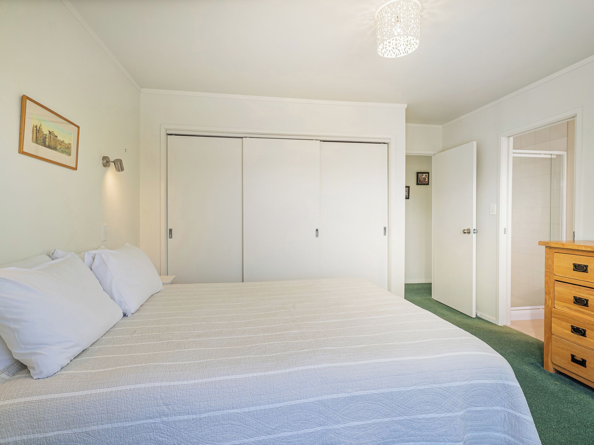 Una camera da letto con un letto grande, un armadio, una cassettiera e un quadro appeso al muro.