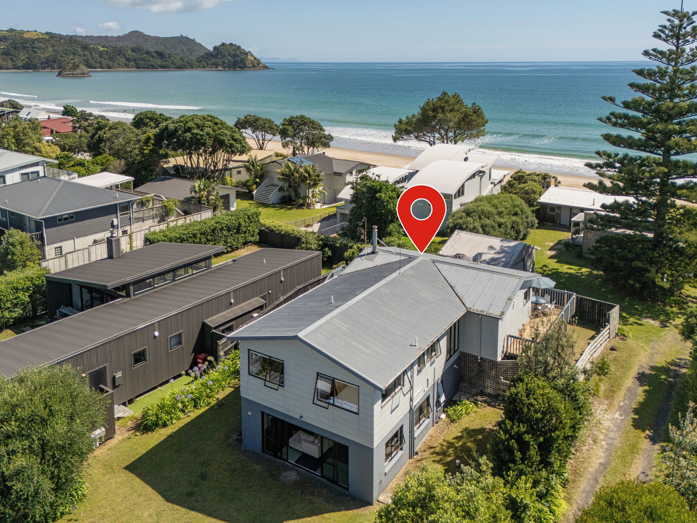 A modern residential area with houses, a beach, and a view of the ocean.