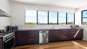 A modern kitchen with a large window, stainless steel appliances, and a dishwasher. - Villa Vista 1 Peregian Beach (Peregian Beach)