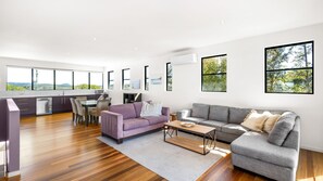 A spacious living area with a dining table, sofas, and a kitchen in the background. - Villa Vista 1 Peregian Beach (Peregian Beach)