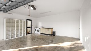 Ruime kamer met betonvloer, een wasmachine, een kast en een plankensysteem.