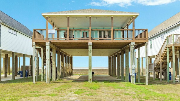 A building with a covered balcony and a staircase leading to a second floor.