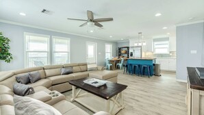A modern living room with a sectional sofa, a coffee table, and a kitchen area with bar stools.