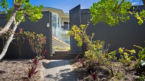 A modern house with a glass door leading to a covered outdoor area. - Old Salt Beach House Marcus Beach (MARCUS BEACH)