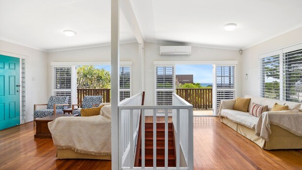 A spacious living area with a wooden staircase, a teal door, and a view of the outdoors. - Piper's Bend Peregian Beach (Peregian Beach)