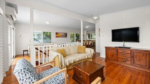 A spacious living area with a sofa, patterned armchair, wooden coffee table, and a TV on a wooden cabinet. - Piper's Bend Peregian Beach (Peregian Beach)