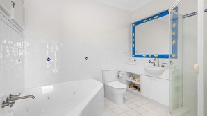 A modern bathroom with a bathtub, toilet, and sink. - Notre Reve 2 Peregian Beach (PEREGIAN BEACH)