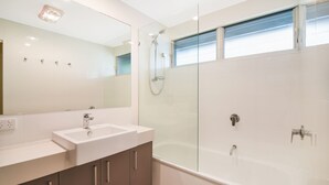 A modern bathroom with a glass-enclosed shower, a double sink vanity, and a large mirror. - Summer Place on Shearwater Peregian Beach (PEREGIAN BEACH)
