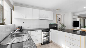Eine moderne Küche mit weißen Schränken, einer schwarzen Arbeitsplatte, einem Herd, einem Backofen und einer Spüle.