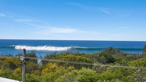 A coastal view with waves, greenery, and power lines. - Costa Del Peregian 3 (PEREGIAN BEACH)