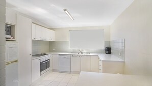Eine moderne Küche mit weißen Schränken, einem Einbauofen, einem Geschirrspüler und einem großen Fenster über der Spüle.