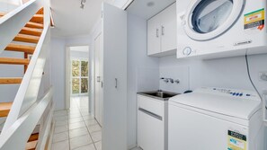 A laundry room with a washing machine, a sink, and a staircase leading to another room. - Parkside on Plover 3 (PEREGIAN BEACH)