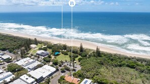 An aerial view of a coastal area with a beach, residential buildings, and a parking lot. - Parkside on Plover 3 (PEREGIAN BEACH)