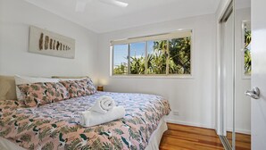 Une chambre avec un grand lit, une fenêtre donnant sur un paysage verdoyant et une porte.